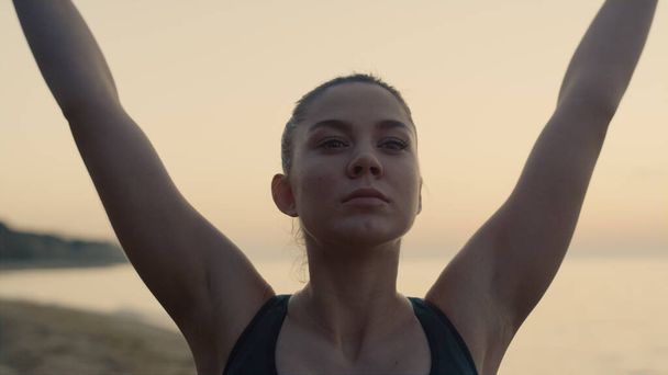 Zárja be a jóga nő edzés homokos tengerparton kora reggel. Vonzó lány felemeli a kezét, hogy légzési gyakorlatokat végezzen a természeten. Magabiztos sportasszony, nyugodt óceán mellett pihen. Energiaharmónia fogalma - Fotó, kép