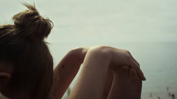 A nő hátradőlve gyakorolja a jógát a tengerparton, közelről. Felismerhetetlen rugalmas lány nyújtózkodó ülő paschimottanasana a természet reggel. Egészséges hölgy tornázik.. - Fotó, kép