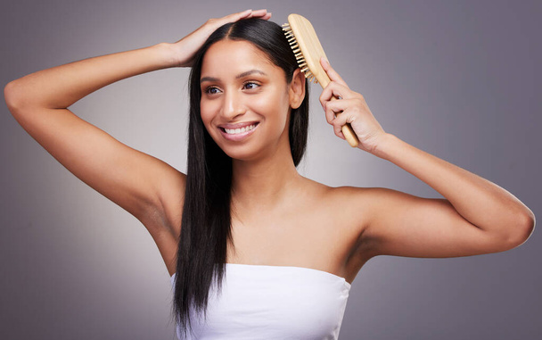 an attractive young woman standing alone in the studio and brushing her hair. - Foto, Imagen