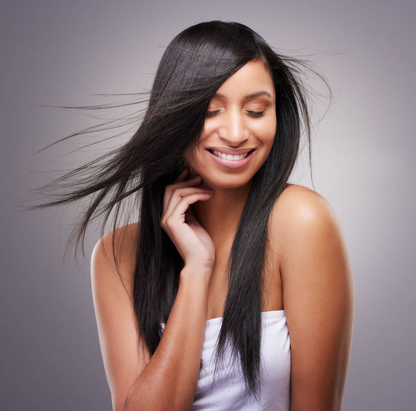 viehättävä nuori nainen seisoo yksin studiossa ja poseeraa, kun hänen hiuksensa puhaltaa tuulessa. - Valokuva, kuva