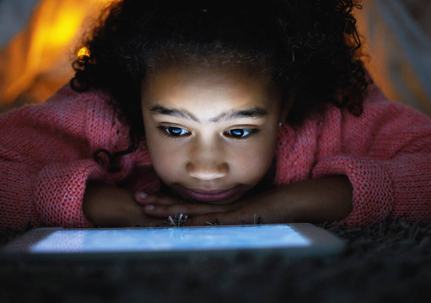 an adorable little girl using a digital tablet during bedtime at home. - Foto, Imagem