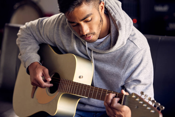 a young man playing an acoustic guitar. - 写真・画像