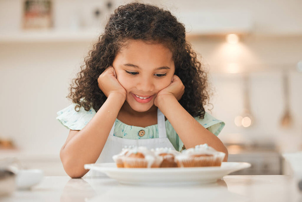 une petite fille attendant patiemment de manger les cupcakes fraîchement cuits. - Photo, image