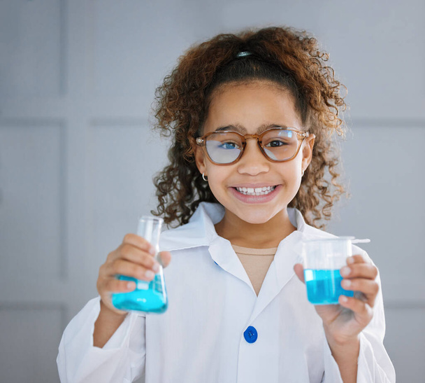 Cropped portrait of an adorable little girl wearing a labcoat while holding two containers of blue liquid. - Foto, immagini