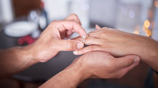 ein unkenntlich gemachter Mann, der seinen Freundinnen zu Hause einen Ring an den Finger legt. - Foto, Bild
