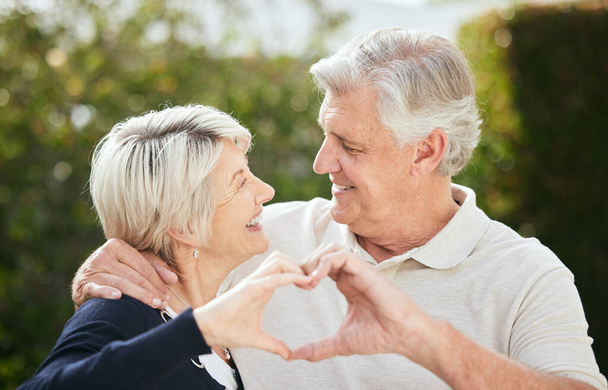 a senior couple forming a heart shape with their hands. - Foto, imagen