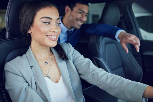 привлекательная молодая женщина, сидящая в новой машине, разговаривая с красивым продавцом машин о сделке. - Фото, изображение