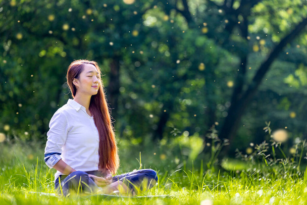 Woman relaxingly practicing meditation in forest to attain happiness from inner peace wisdom for healthy mind and soul in evening light with midge and fire fly insect bokeh background  - Fotoğraf, Görsel