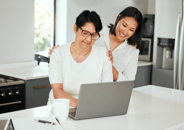 een jonge vrouw met behulp van een laptop met haar oudere moeder tijdens het gaan door de financiën thuis. - Foto, afbeelding