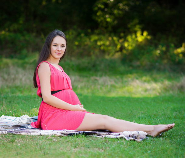 junge schwangere Frau entspannt sich im Park im Freien, gesunde Schwangerschaft. - Foto, Bild