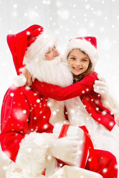smiling girl hugging santa claus with gift at home - Фото, зображення