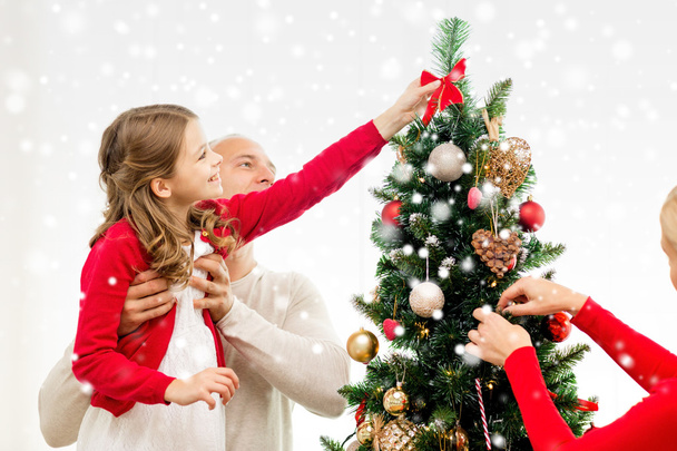smiling family decorating christmas tree at home - Фото, изображение