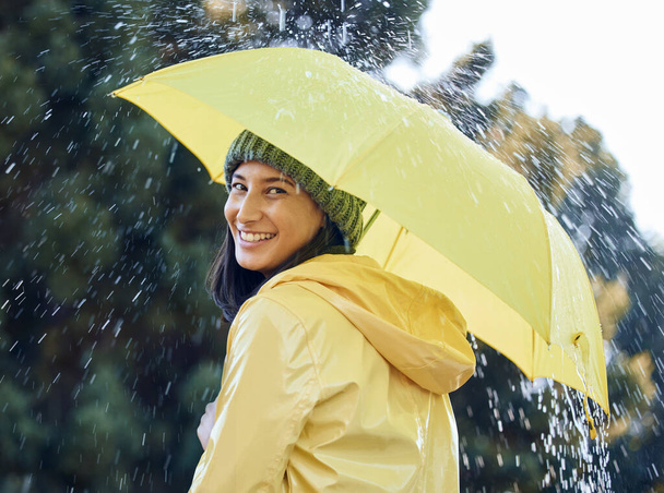 a woman out in the rain with a yellow raincoat an umbrella. - Photo, image