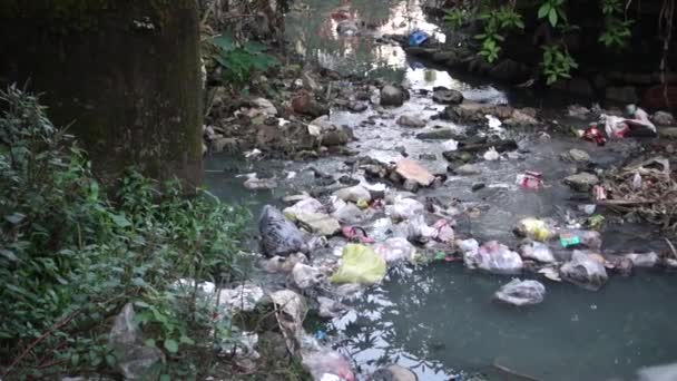 Een goot vol plastic en giftig afval dat in de open lucht stroomt. - Video