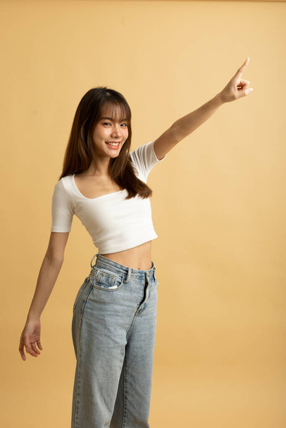 Young Asian girl dress in white shirt and jeans ready to travel on vacation on yellow isolated background - Foto, Imagen