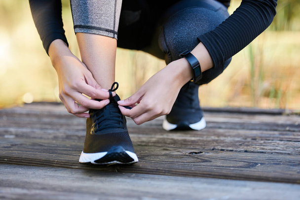 Closeup shot of an unrecognisable woman tying her laces while exercising outdoors. - Foto, Imagen