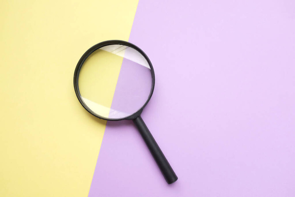 black round magnifying glass on yellow and purple pastel background. used for searching or expanding books. - Foto, Imagem
