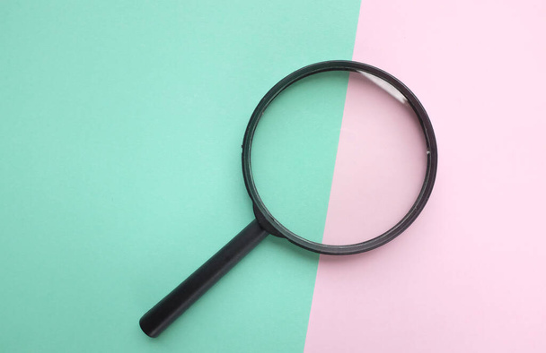 black round magnifying glass on pink and green pastel background. used for searching or expanding books. - Photo, Image