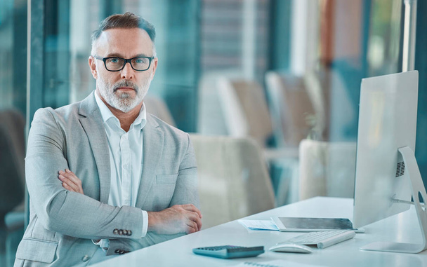 a mature businessman sitting at a desk at work. - Фото, зображення