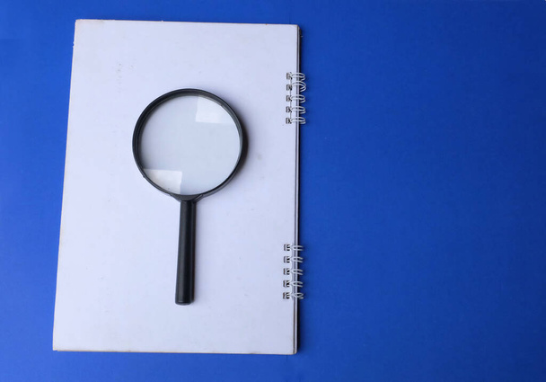 magnifying glass search symbol on notepads isolate a blue background - Zdjęcie, obraz