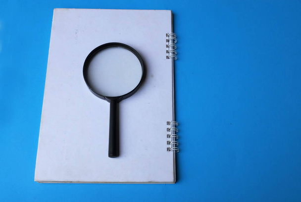 magnifying glass search symbol on notepads isolate a blue background - Photo, Image