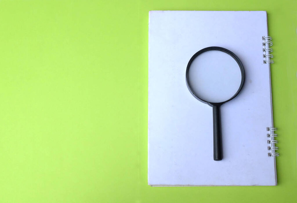 magnifying glass search symbol on notepads isolate a green background - Photo, Image