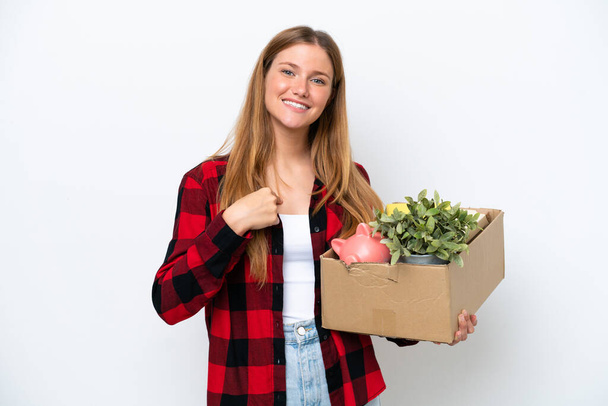 Young caucasian woman making a move while picking up a box full of things isolated on white background with surprise facial expression - Foto, Imagen
