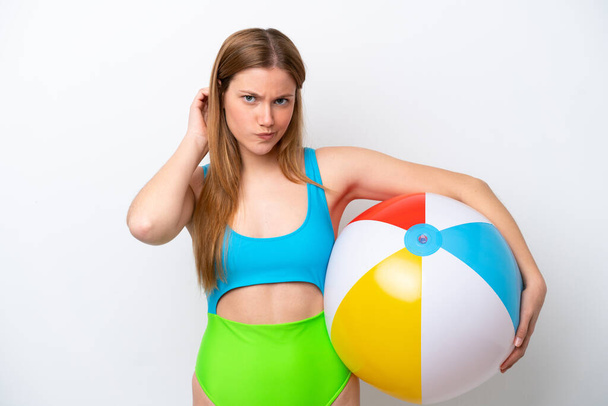 jonge vrouw holding strand bal in vakantie geïsoleerd op witte achtergrond met twijfels - Foto, afbeelding