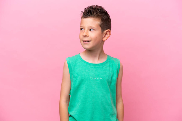 Little caucasian boy isolated on pink background looking to the side and smiling - Valokuva, kuva