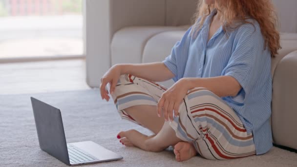 nerozpoznatelná žena sedící na podlaze se zkříženýma nohama sledující online jógu nebo kurz na notebook meditace v apartmánu ranní rutina pro klid - Záběry, video
