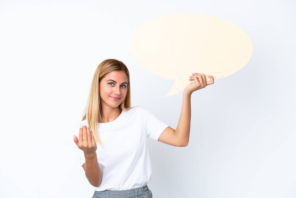 Blonde Uruguayan girl isolated on white background holding an empty speech bubble and doing coming gesture - Foto, Imagem