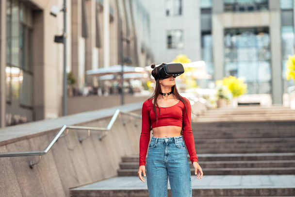 A woman in a virtual reality helmet walks down the street - Photo, image