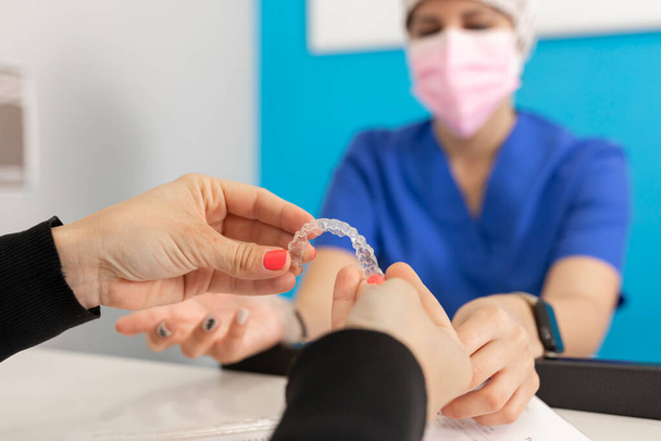 Hands of a manager woman showing to one of her employees some aspects of invisible orthodontics at the dental clinic - Photo, image