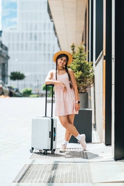 Молодая красивая женщина с чемоданом на фоне современного города - Фото, изображение