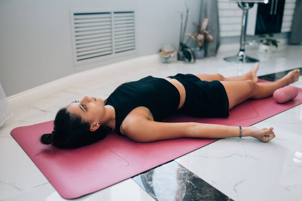 Jeune femme pratiquant dans un studio de yoga. Shavasana ou pose du corps est la fin d'une classe ou d'une pratique
. - Photo, image