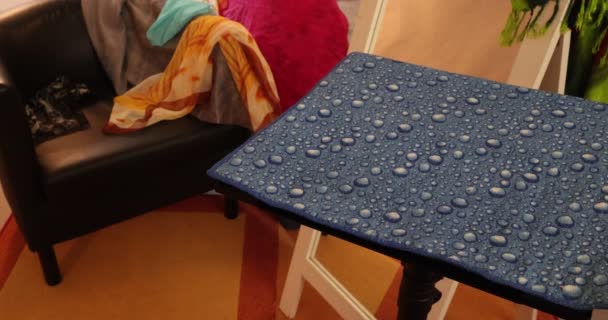Ενηλίκων γυναικεία χέρια τοποθέτηση ενός ίσιωμα σιδήρου, μαύρο πινέλο και καφέ χτένα σε ένα μικρό τραπέζι με μια μπλε επιφάνεια, για ίσιωμα των μαλλιών, δωμάτιο με πάγκο, έναν καθρέφτη και διάσπαρτα πολύχρωμα κασκόλ - Πλάνα, βίντεο