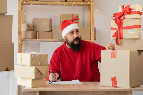 стартап-підприємець малий бізнес Санта Клаус позаштатний чоловік, що працює з коробкою, молодий власник малого бізнесу офіс онлайн-ринку упаковки коробка для різдва, мазз концепція доставки електронної комерції
 - Фото, зображення