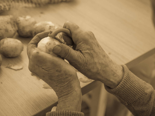 Старые, руки чистят картошку. - Фото, изображение