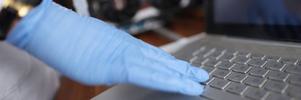 Крупный план профессионального техника, трогающего клавиатуру ноутбука в стерильных перчатках. Проверьте устройство на скрытый сбой. Техническое обслуживание - Фото, изображение