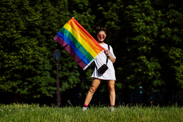 Giovane donna con bandiera orgoglio lgbt nel parco. - Foto, immagini