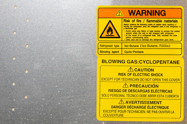 Warning. Blowing gas. Cyclopentane. Blowing agent.  Warning label on household appliances. Refrigerator repair in the workshop. Service maintenance. The back side of equipment. Copy space for text - Photo, image