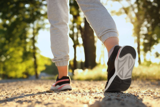 Woman running on pathway outdoors in morning, closeup - Foto, afbeelding