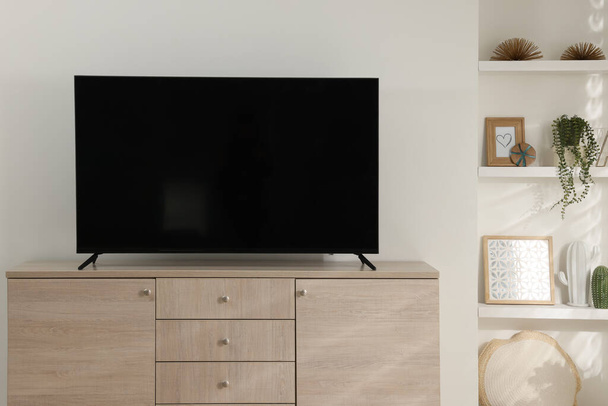 Stylish wide TV set on wooden cabinet in room - Foto, afbeelding