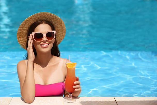 Beautiful young woman with cocktail in swimming pool. Space for text - Foto, imagen