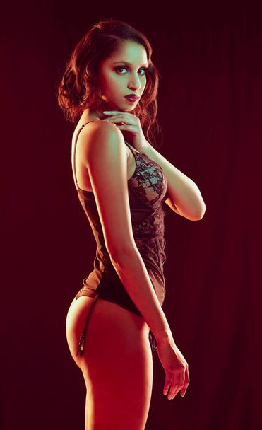 Cropped portrait of a beautiful young woman posing in lingerie against a red background. - Fotoğraf, Görsel