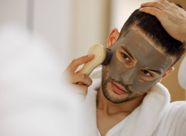 a handsome young man giving himself a facial at home. - Foto, Imagen