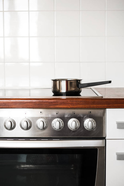 a metal saucepan stands on the stove in the kitchen. kitchen accessories - Photo, Image