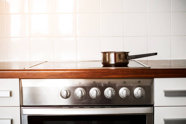 a metal saucepan stands on the stove in the kitchen. kitchen accessories - Fotografie, Obrázek