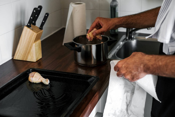 ein erwachsener Mann mariniert Fleisch für das Abendessen im Ofen - Foto, Bild