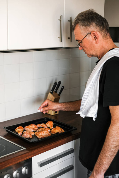 adult man cooking marinated chicken at home - 写真・画像